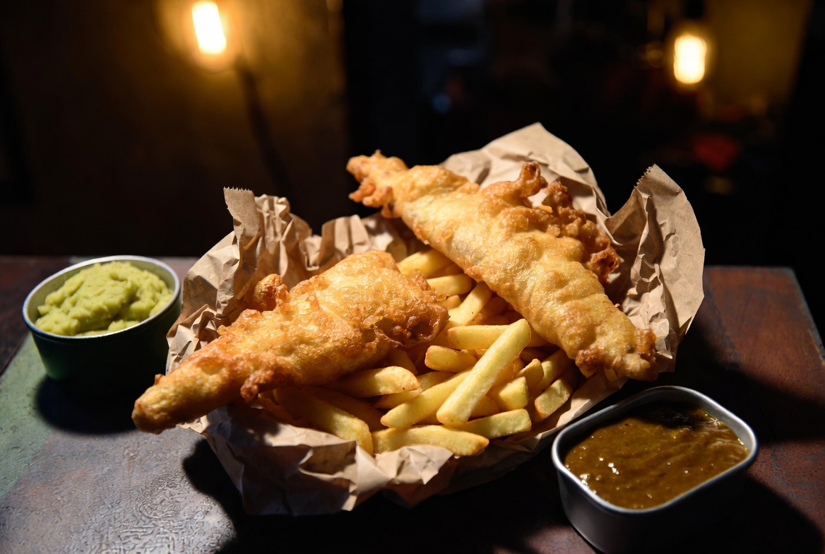Golden battered fish and chips with mushy peas and curry sauce